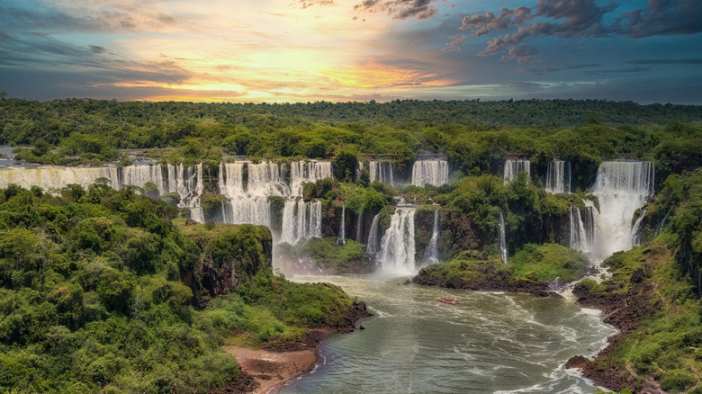 An aerial view of Iguazú Falls surrounded by lush rainforest at sunset