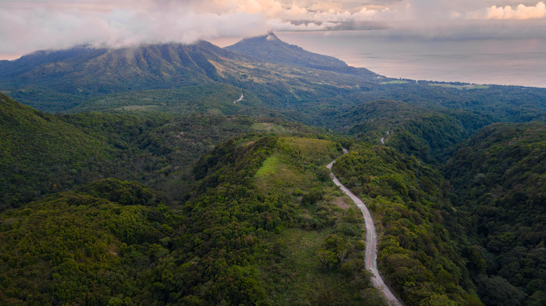 Aerial view of Camiguin Island in the Philippines, lush green mountains, and a road winding through them