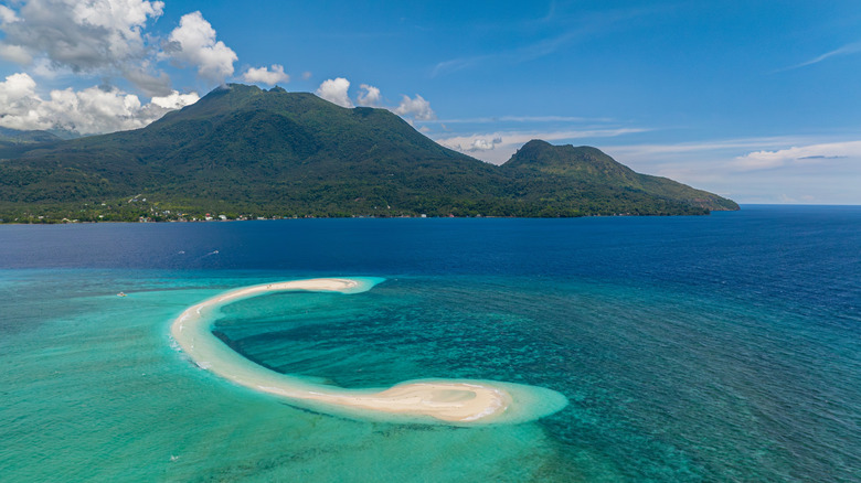 Aerial view of White Island in Camiguin, Philippines with turquoise ocean surrounding it and views of the mountains behind