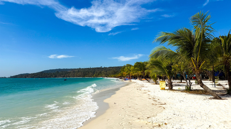 White sand, blue ocean, and palm trees on a crescent beach in Cambodia
