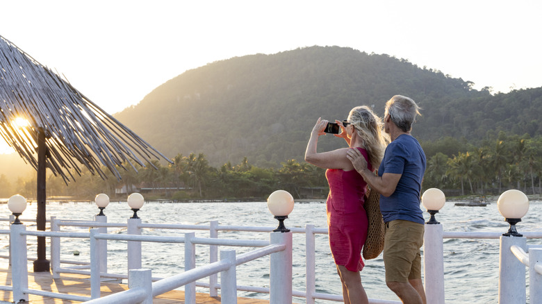 A mature couple on a wood deck overlooking the sea and mountains on Phu Quoc island, Vietnam