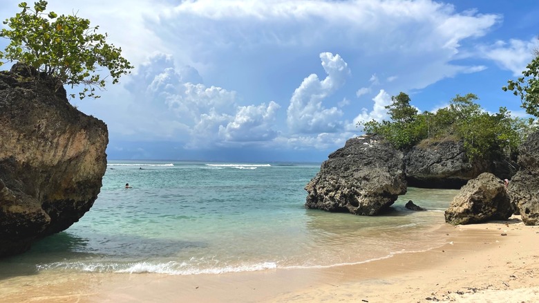 Rocks and a sandy beach with towering clouds over the ocean, Padang Padang Beach on Bali.