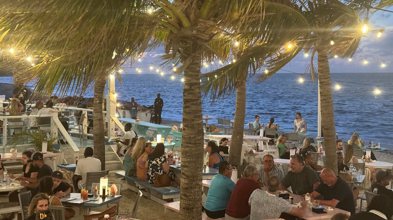 Da Conch Shack Restaurant and Rum Bar with its ocean-front tables on the sand and palm trees strung with lights