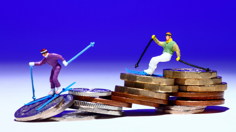 People skiing down a pile of coins