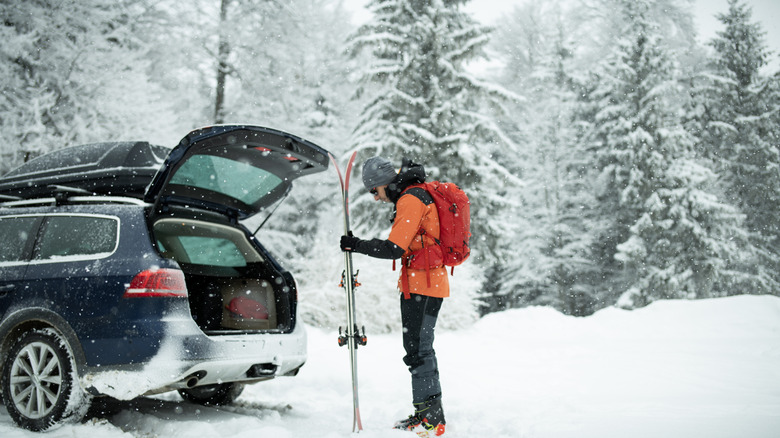 A man unpacking ski equipment from the tailgate of a car