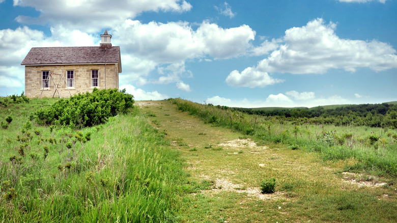 A trail leading to a small brick building on a green grass field
