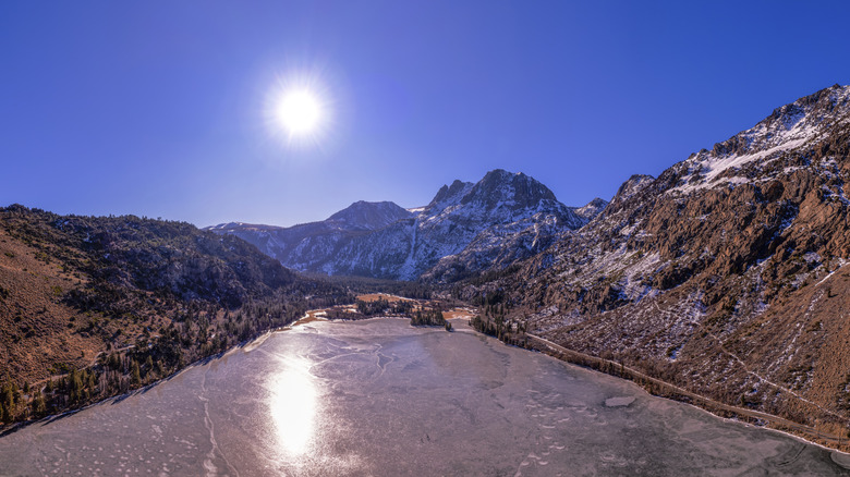 A view over Silver Lake in the June Lake Loop, California, with a low sun shining in the blue sky