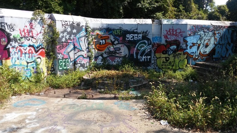 Graffiti-covered wall at Fort Armistead, with cement overgrown with weeds in the foreground