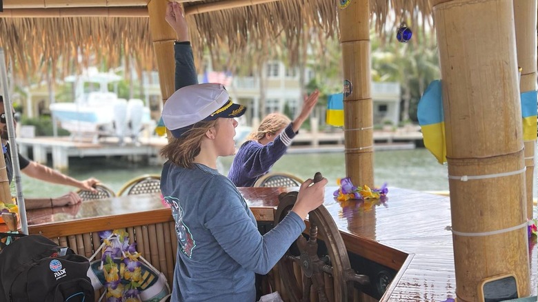 A woman behind the wheel inside the bar of the floating tiki hut