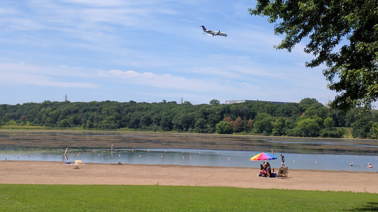 A plane flying overhead at the sandy beach at Snelling Lake, Fort Snelling State Park