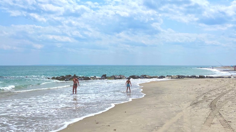 Two people walking along the water at Fort Tilden Beach, Queens, New York