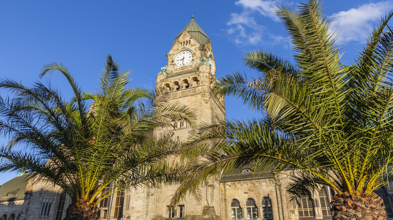 Clocktower and train station with palm trees in Metz, France on a sunny day