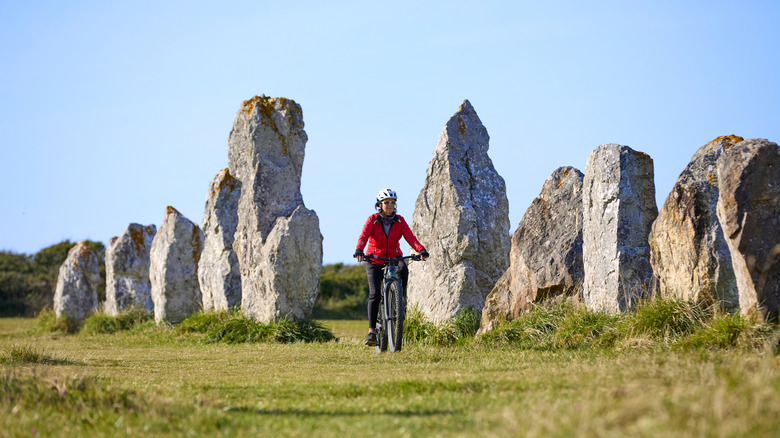 Woman cycling between the megalithic stones at Carnac