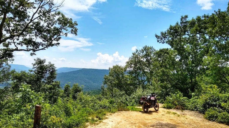 A motorcycle parked at an overlook with views of the lush rolling hills inside Franklin State Forest in Tennessee