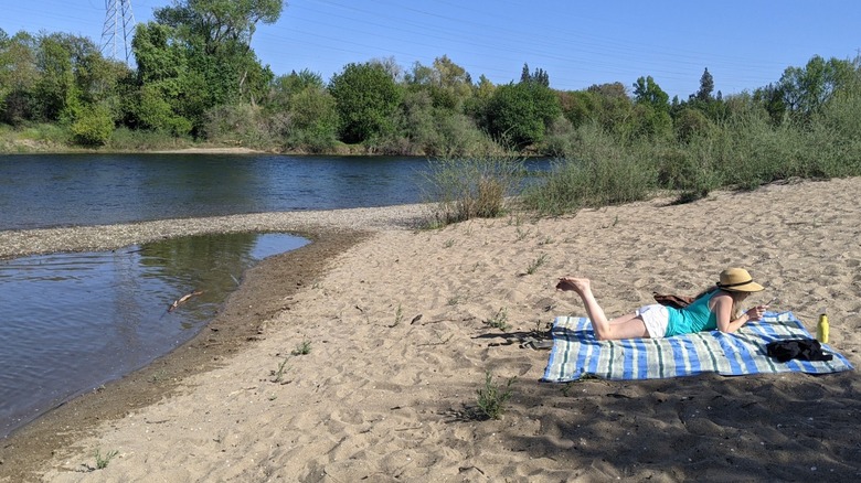 A woman lounges on a towel at Paradise Beach in Sacramento, California.