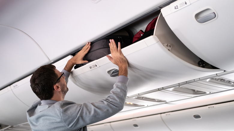 Man accessing overhead bin on plane