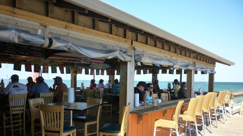 People sitting at Fish Heads Bar and Grill with the ocean in the background, South Nags Head, Outer Banks, North Carolina