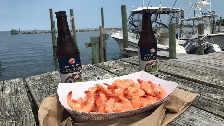 A basket of spiced shrimp and two beers, on a weathered picnic table overlooking Hatteras Village's fishing harbor on Hatteras Island in the Outer Banks