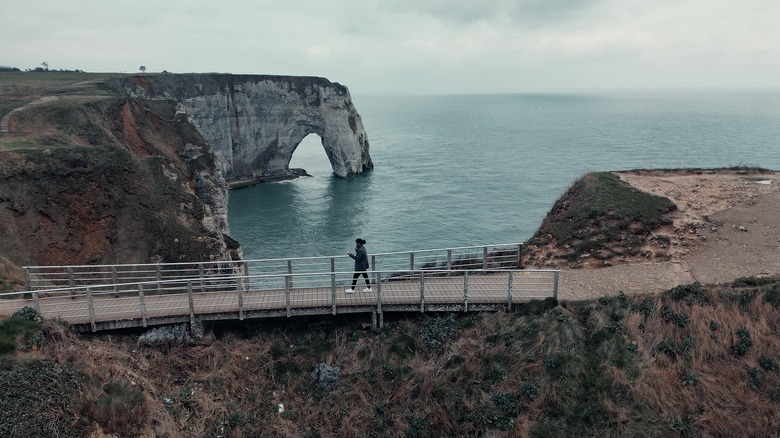 Tourists walks along a bridge at the cliffs of Etretat