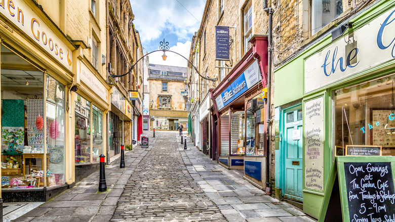 Independent shopfront along Charlotte Hill in Frome, a cobblestoned street with historic buildings and stores.