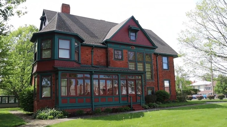 The 19th century Brownella Cottage with red bricks, green trim, and a green lawn