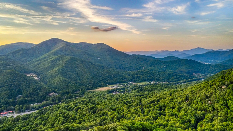A view of green hills, trees, and a colorful sky in Maggie Valley