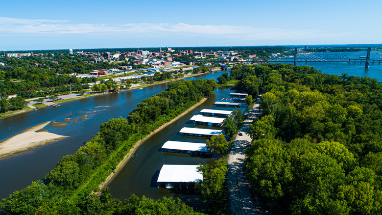aerial view of blue water and green trees with bridge behind it