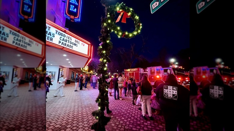 sidewalk image of people outside Royal Theater during holiday season at night