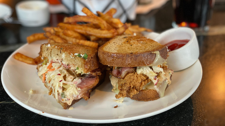 A fried catfish sandwich on a plate with fries and ketchup