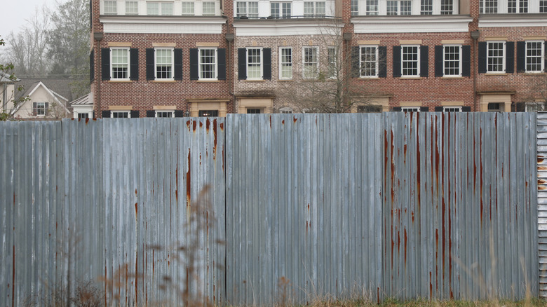 A metal fence with a brick apartment building