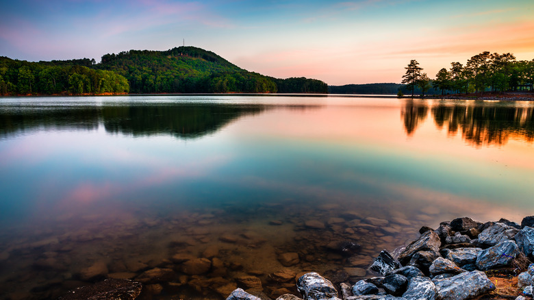Sunrise over Lake Allatoona at Red Top Mountain State Park with trees along the shoreline and placid water.