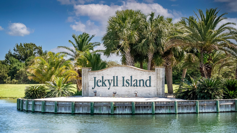 Entrance sign to Jekyll Island on the water with palm trees