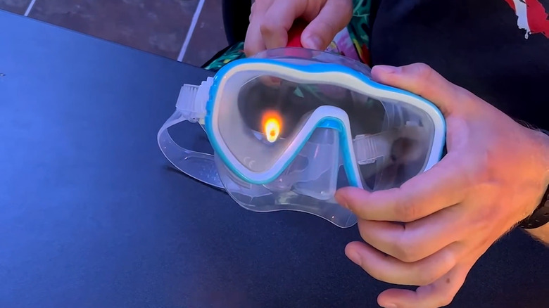 Using a lighter to burn off residue on inside of scuba mask