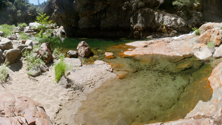 Shallow end of God's Bath along a rocky riverbank in Stanislaus National Forest, California