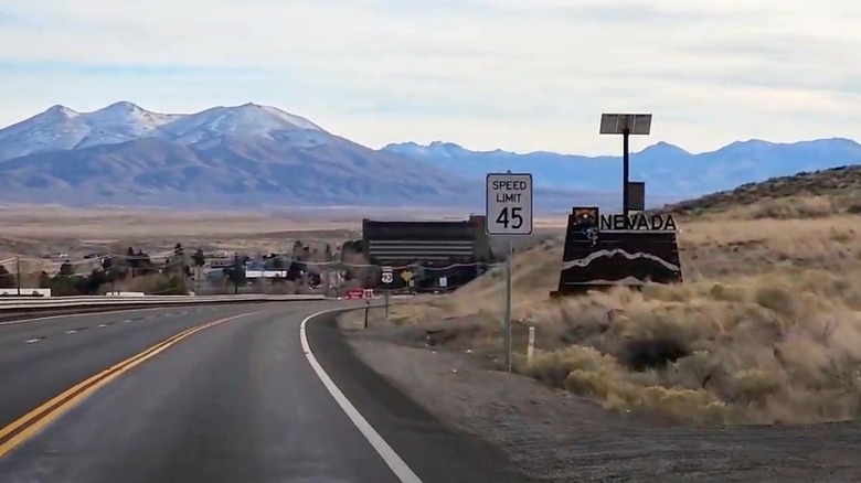 The road to Jackpot, Nevada with the mountains in the background and the Nevada state sign