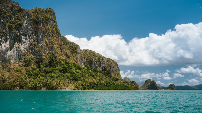 The rocky limestone cliffs of Lagen Island rise up from the vibrant turquoise water of Bacuit Bay