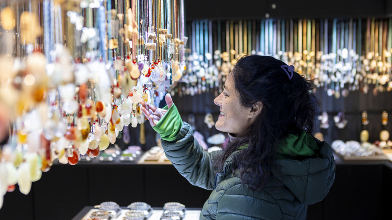 A woman examining hanging jade necklaces in a jewelry shop