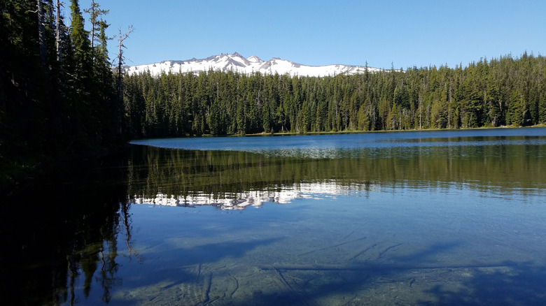 View across Yoran Lake clear water and snowy mountain peak in Oregon