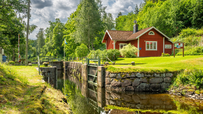 Typical red house in the Swedish Dalsland region countryside overlooking verdant canal docks.
