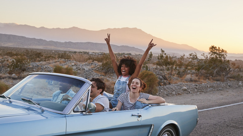 Four people laugh and smile in convertible in desert United States