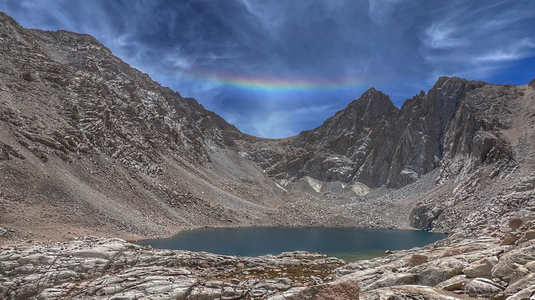 Gravel and granite sloping into Consultation Lakes deep blue-green waters with a prism above a mountain crevasse
