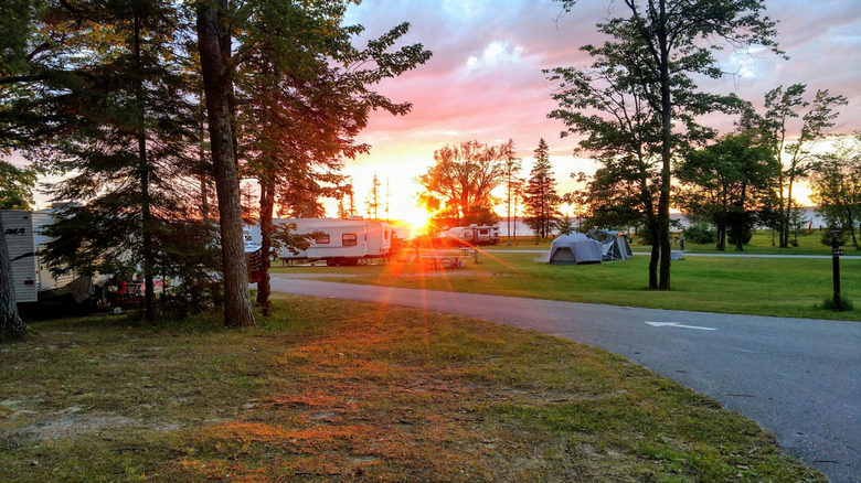 Tents and campers at Burt Lake State Park in Michigan with sunset