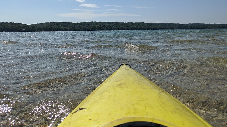 The front of a yellow kayak facing out towards the middle of Lime Lake with clear water in front