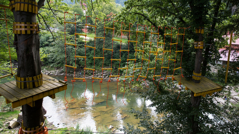 An obstacle course with ropes suspended over a river at an adventure park