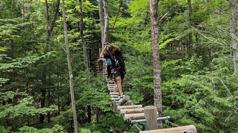 A man navigates a hanging bridge course in Adirondack Extreme adventure park in upstate New York