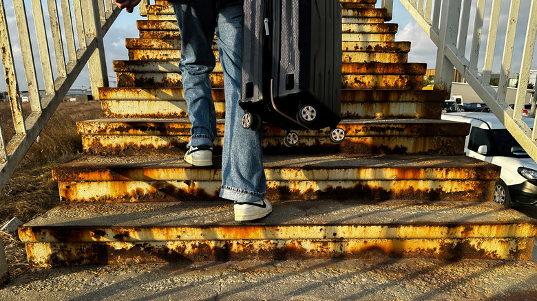 Someone taking a suitcase up stairs
