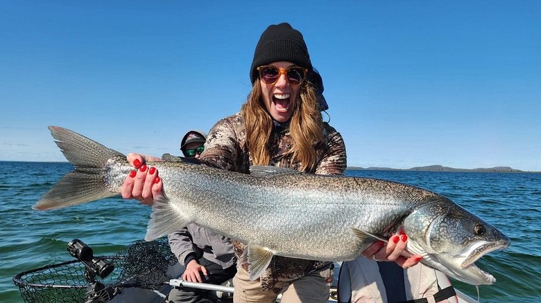 A woman excitedly smiling with an open mouth holding a large fish