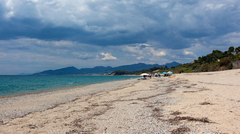 The sandy shores of Monolithi Beach in Greece framed by mountains in distance