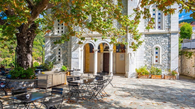 Vamvakou, Greece- October 28 2023: The central square with the century-old plane trees and the three-story church dedicated to the Dormition of the Virgin, Agios Charalambos and Agia Paraskevi