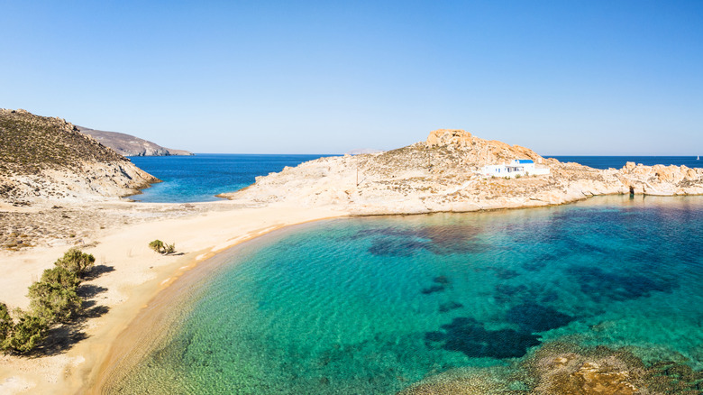 Turquoise water laps sandy isthmus with church at Agios Sostis beach on Serifos